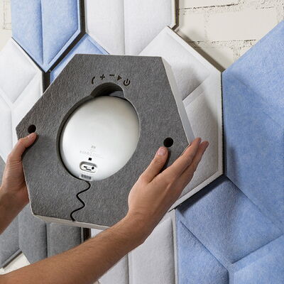 Hands Installing a Hexagonal Acoustic Panel on a Wall