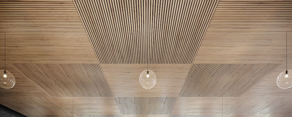 Modern wooden ceiling with linear patterns and hanging pendant lights, enhancing interior aesthetics.