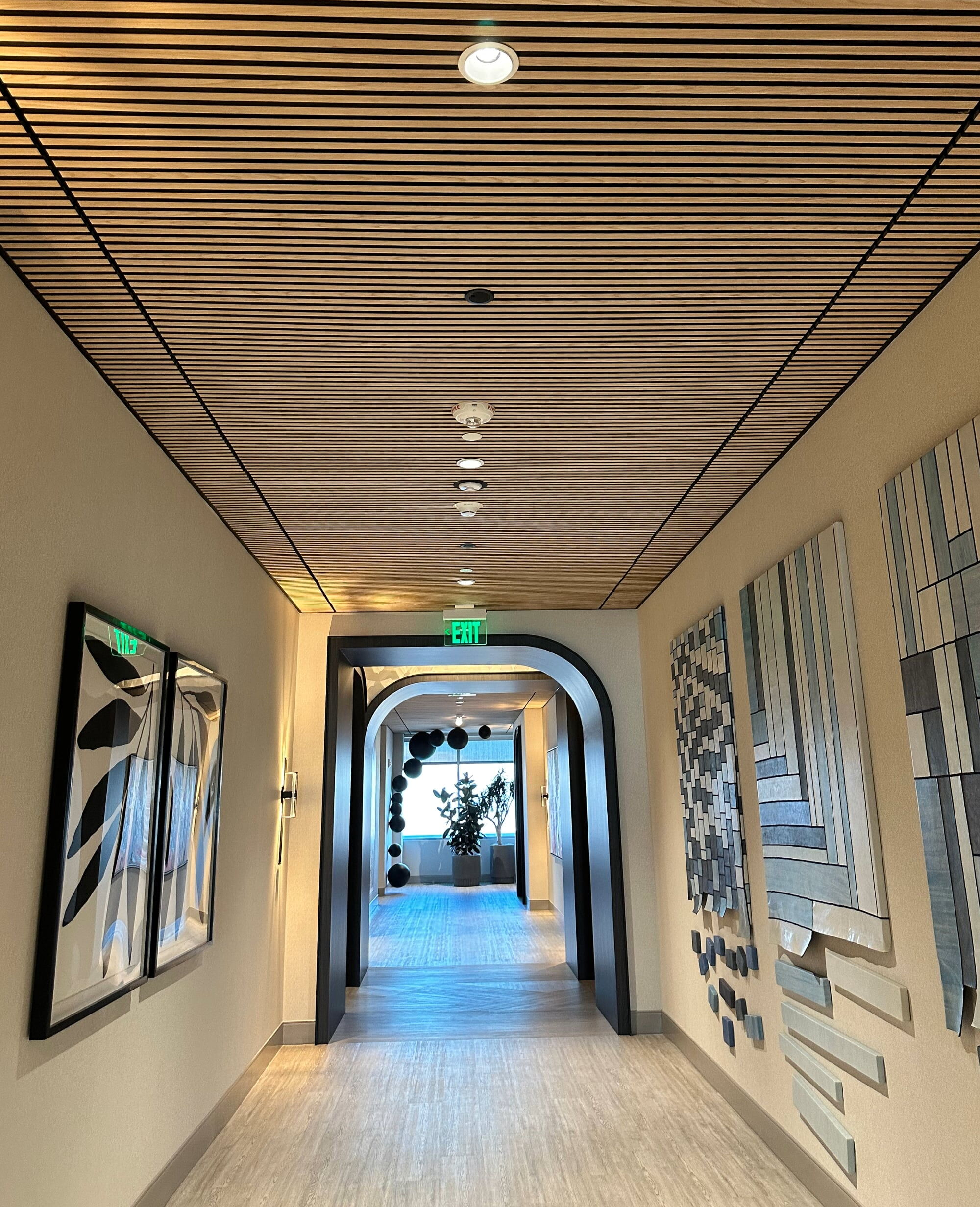 Modern Office Corridor Featuring Wooden Slats Ceiling and Artistic Wall Panels