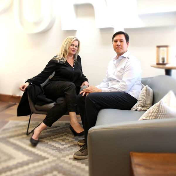 Two Professionals Sitting in an Office Lounge Area Discussing Work