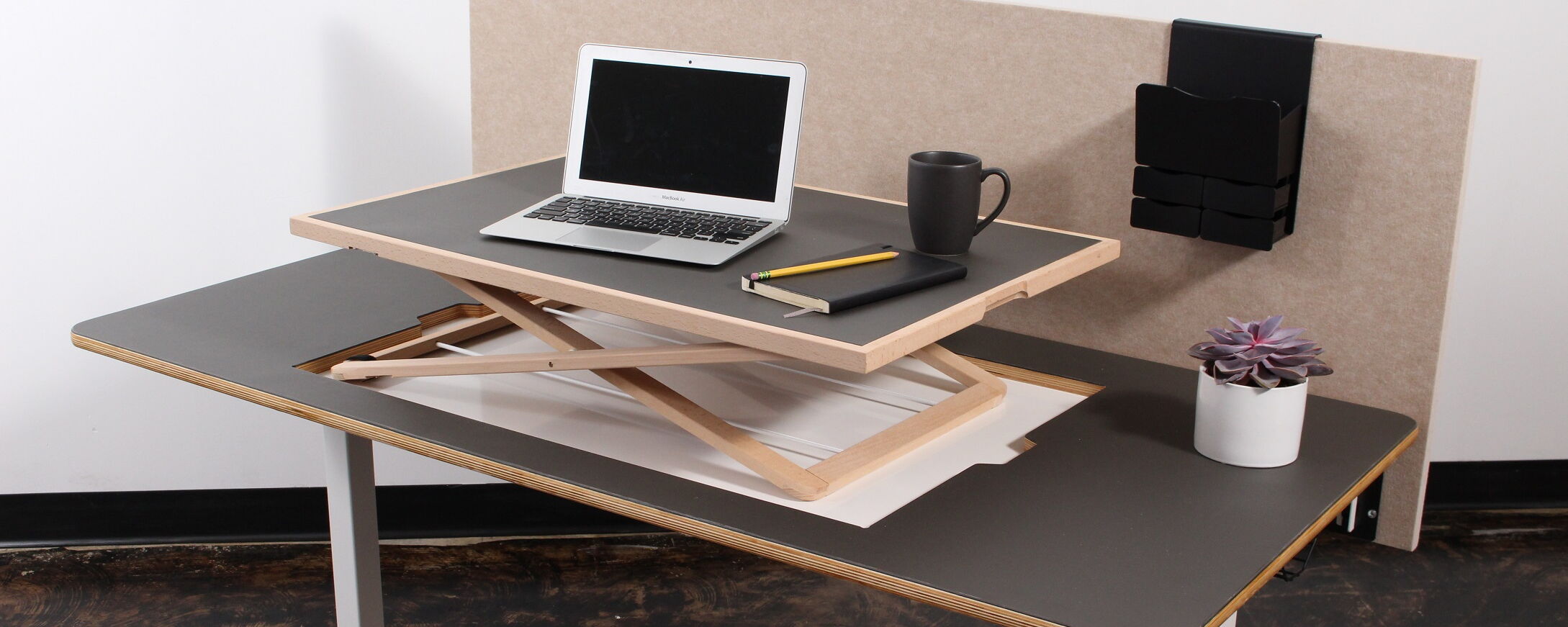 A Contemporary Workspace with an Adjustable Standing Desk, Laptop, Notebook, Mug, and Decorative Plant