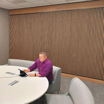 Man in Purple Shirt Working on a Tablet at a Modern Conference Table