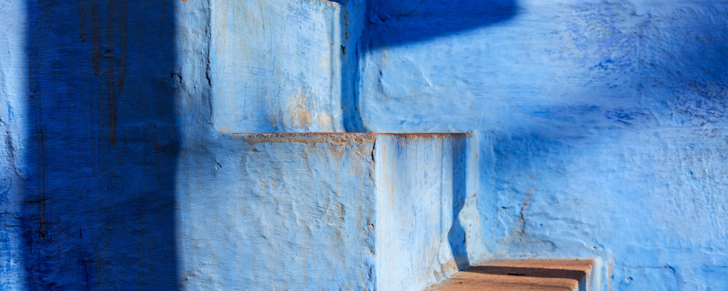 Vibrant Blue Stairs and Walls with Shadows Under Sunlight